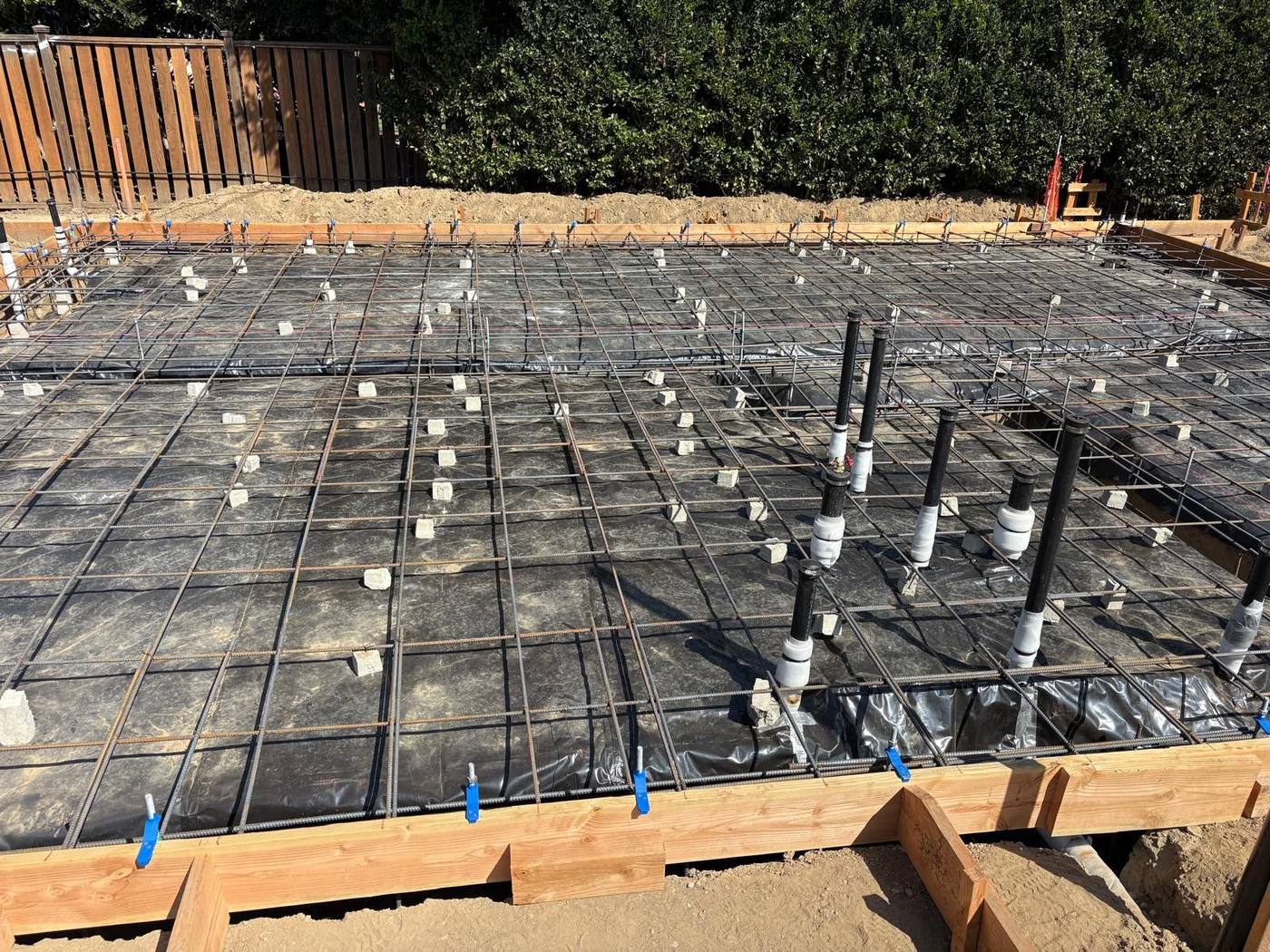 Rebar grid over a vapor barrier with plumbing and anchor bolts