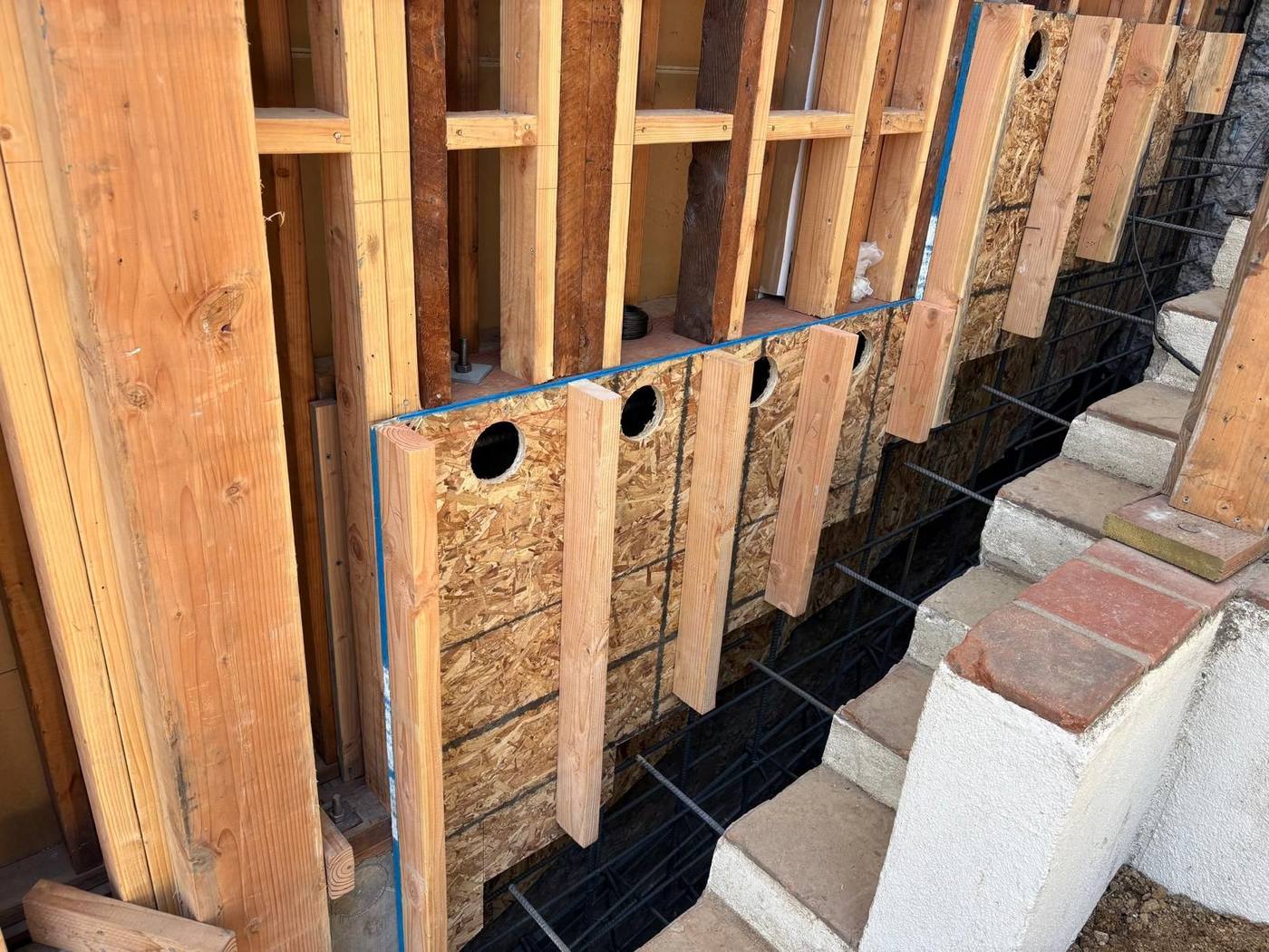 Wood forms with pour holes under an existing house wall
